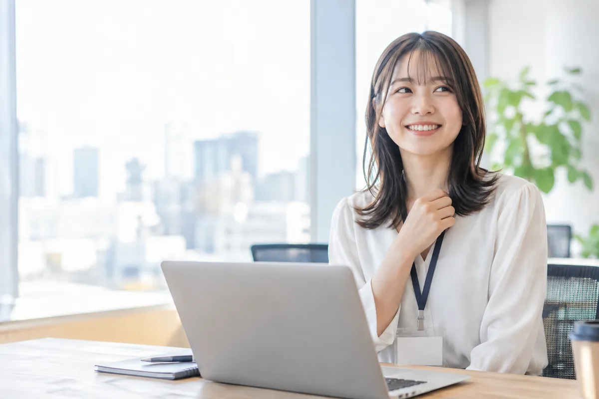 新しい社員証をつけて笑う女性